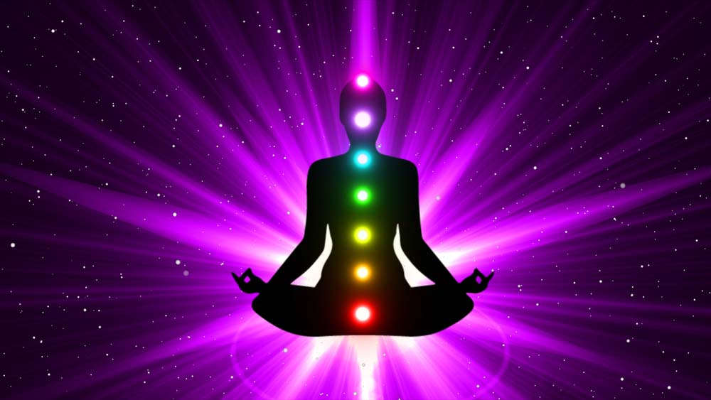 Seated figure showing chakras with a purple background and light extending from the figure part of a healing journey.